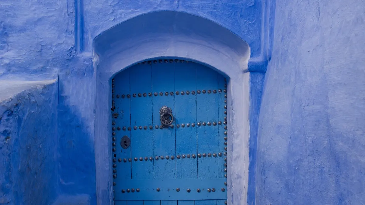 Porta de madeira azul em arco numa parede azul
