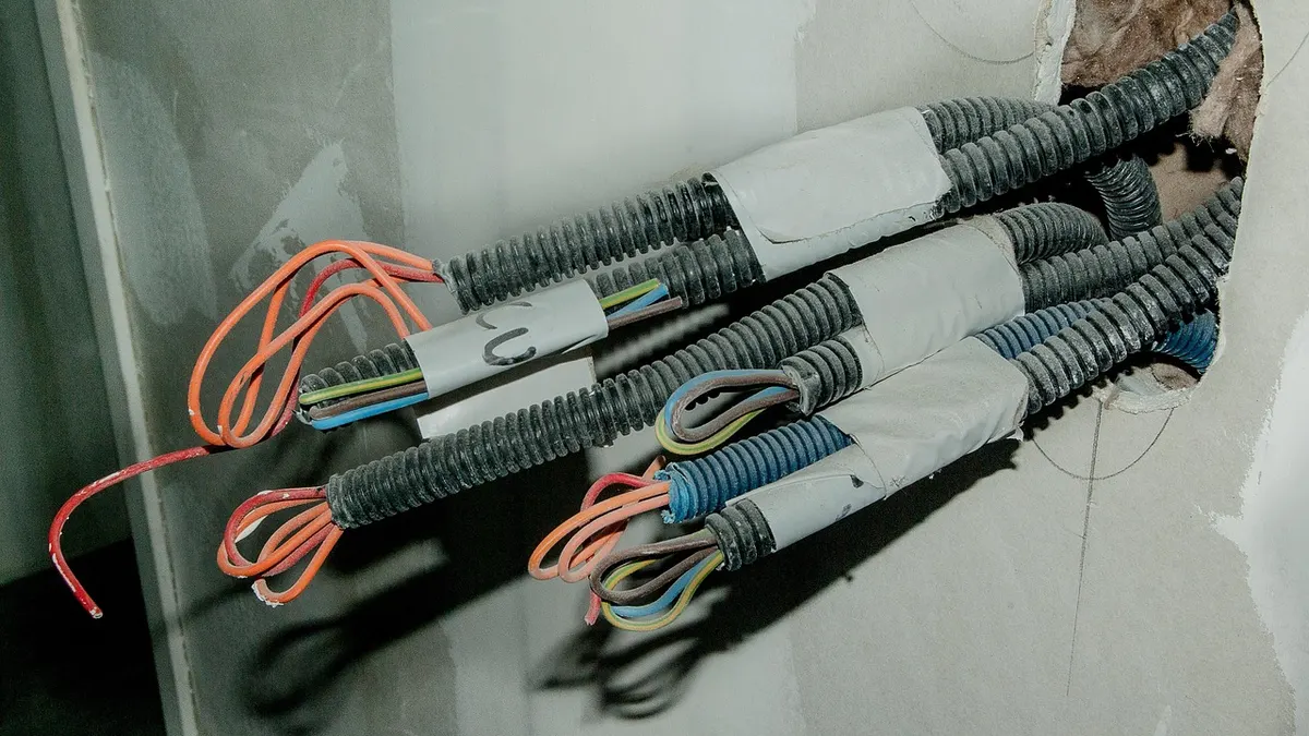 Eletrodutos e fios elétricos saindo de abertura na parede